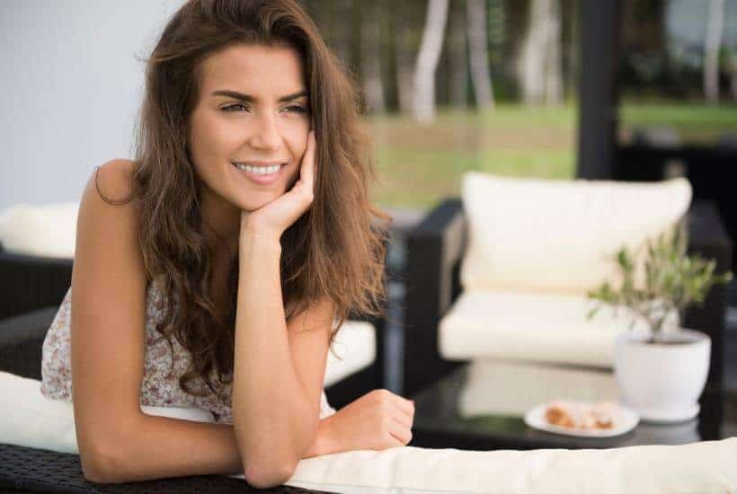 a woman leaning against a counter with her hand under in her chin smiling featured image for Finding Peace And Joy After Loss