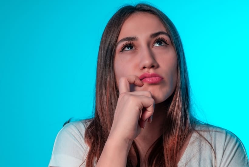 a woman wearing a white shirt with finger touching her cheek looking upward featured image for Storms of Life: 6 Questions We Are Tempted to Ask God