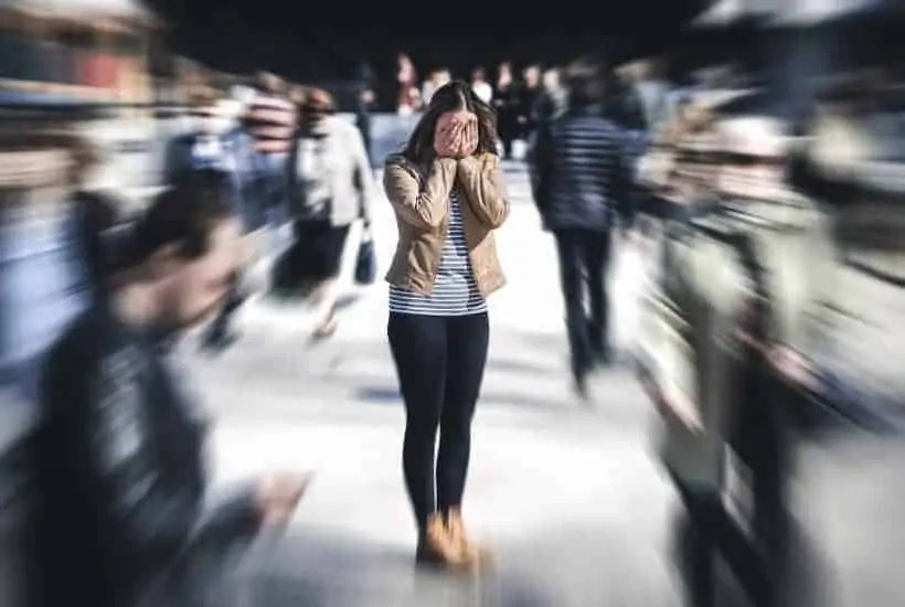 face your fears an image of a woman full of anxiety hiding her face while she's surrounded by group of people