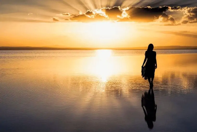 an image of a woman walking the beach with a golden sunset in the background featured image for Do You Know The Importance Of Walking With God?