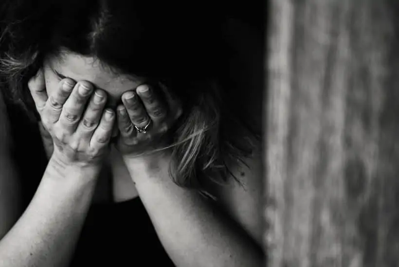 an image of a woman with her hands over her face with her head down featured image for What Does the Bible Say About Fear?