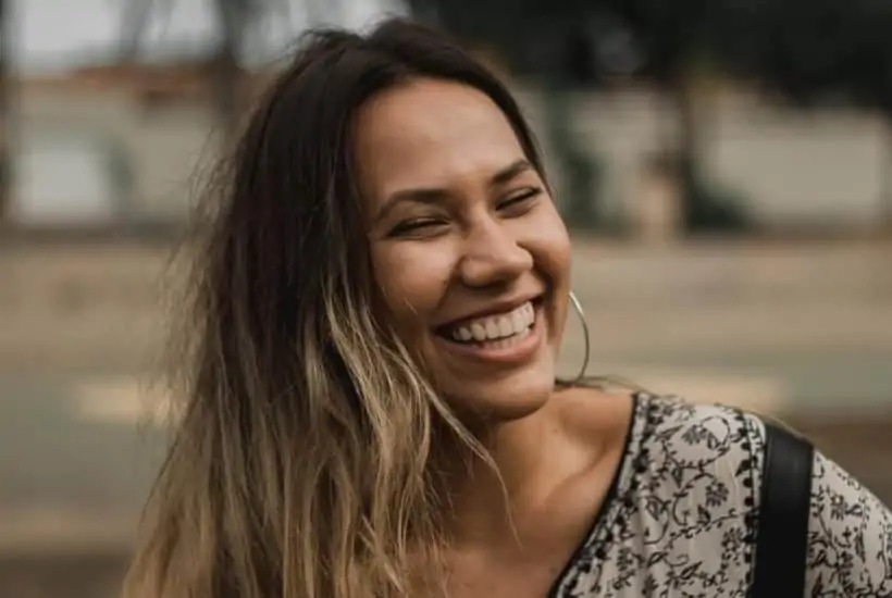 an image of a woman laughing wearing a green and brown shirt. featured image for What Does the Bible Say About Laughter?